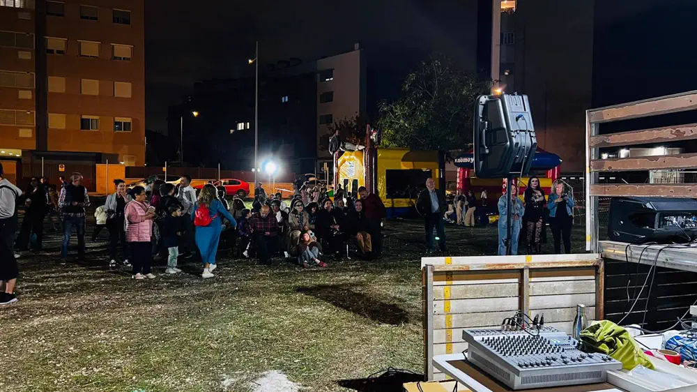 Familias y voluntarios reunidos frente al escenario y los hinchables durante la barbacoa solidaria de San Bernardo.